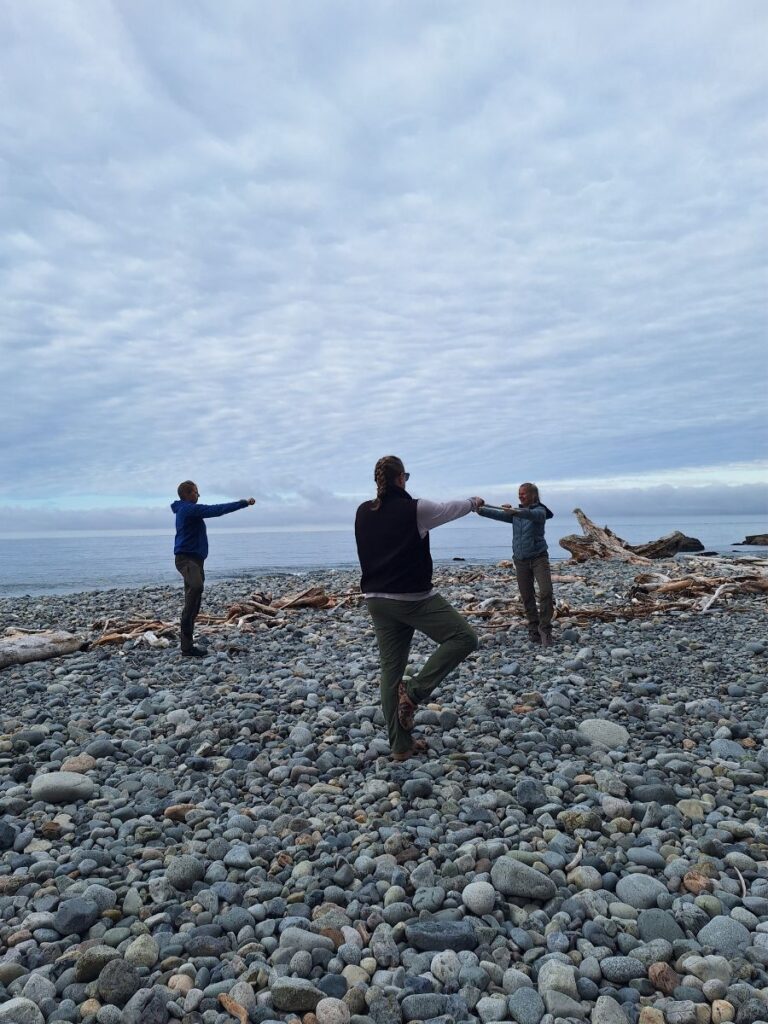 Three hikers on the beach doing yoga